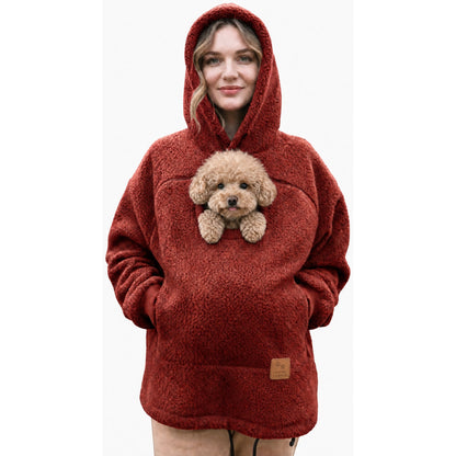 Woman wearing the Cudaroo pet pouch hoodie in red with a small poodle in the chest pouch